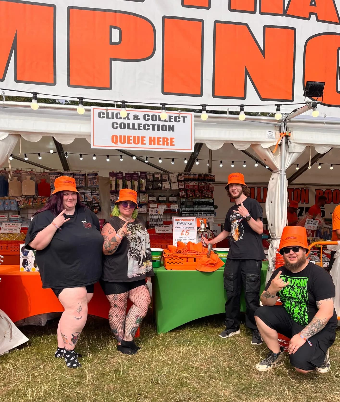 Four Fat Franks staff in orange bucket hats outside the stall, under the click and collect queue sign, beside the charity bucket hat table.